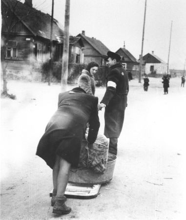 A Jewish policeman helps two women move their belongings to new quarters in the Kovno ghetto